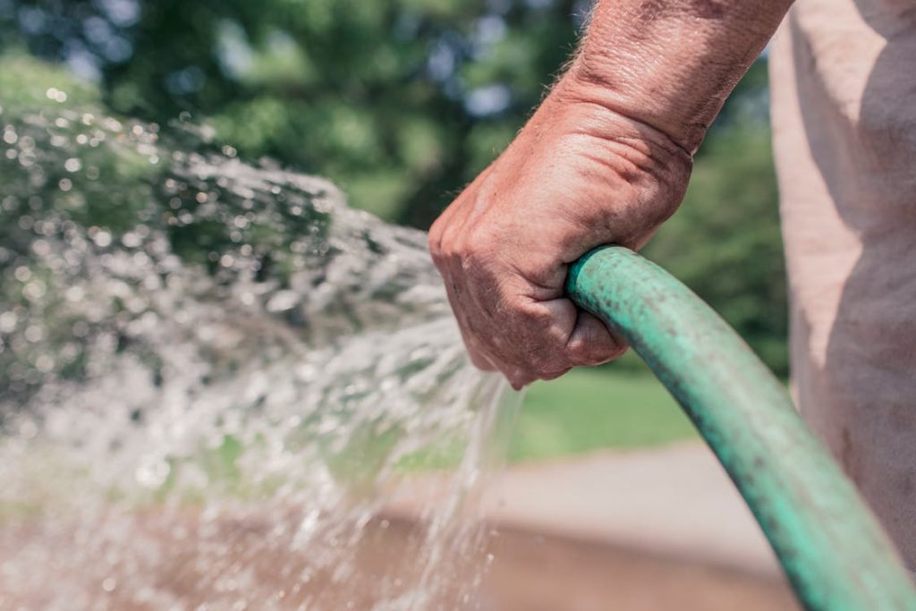 using a waterhose to hand water a garden